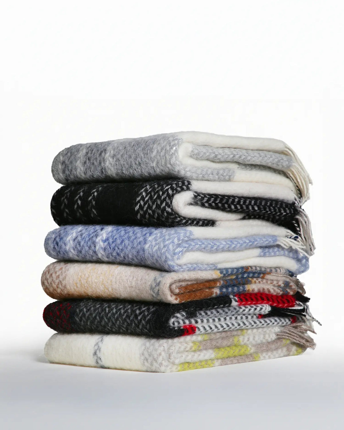 Stack of various patterned sweaters on a white background